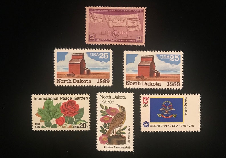 Pu&ograve; includere: Una collezione di francobolli vintage con immagini del Dakota del Nord, tra cui un elevatore di cereali, una mappa dello stato, un'allodola dei prati, una rosa selvatica di prateria e la bandiera dello stato. I francobolli sono degli anni '70 e '80.