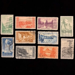 May include: A collection of vintage U.S. postage stamps featuring various scenic landscapes. Stamps depict mountains, geysers, and lakes in shades of green, blue, orange, and purple. Denominations range from 1 to 10 cents.