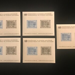 May include: Four sheets of paper with United Nations stamps commemorating the 15th anniversary of the United Nations. The stamps feature the text "We the Peoples of the United Nations" and the United Nations logo. The stamps are in blue and brown.
