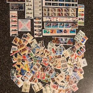 May include: A large collection of vintage postage stamps from around the world. The stamps feature a variety of subjects, including trains, animals, and historical figures. Some of the stamps are in mint condition, while others show signs of wear and tear.