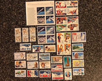 Könnte beinhalten: Eine Sammlung von alten Briefmarken mit verschiedenen Motiven, darunter Flugzeuge, Menschen und Landschaften. Die Briefmarken sind in Reihen und Spalten auf einer dunkelbraunen Oberfläche angeordnet. Der Text "20th Universal Postal Congress" ist auf einer der Briefmarken sichtbar.