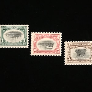 May include: Three vintage United States postage stamps. The first stamp is green and features a train bridge. The second stamp is red and features a train. The third stamp is gray and features a steam engine. The stamps are all in good condition.