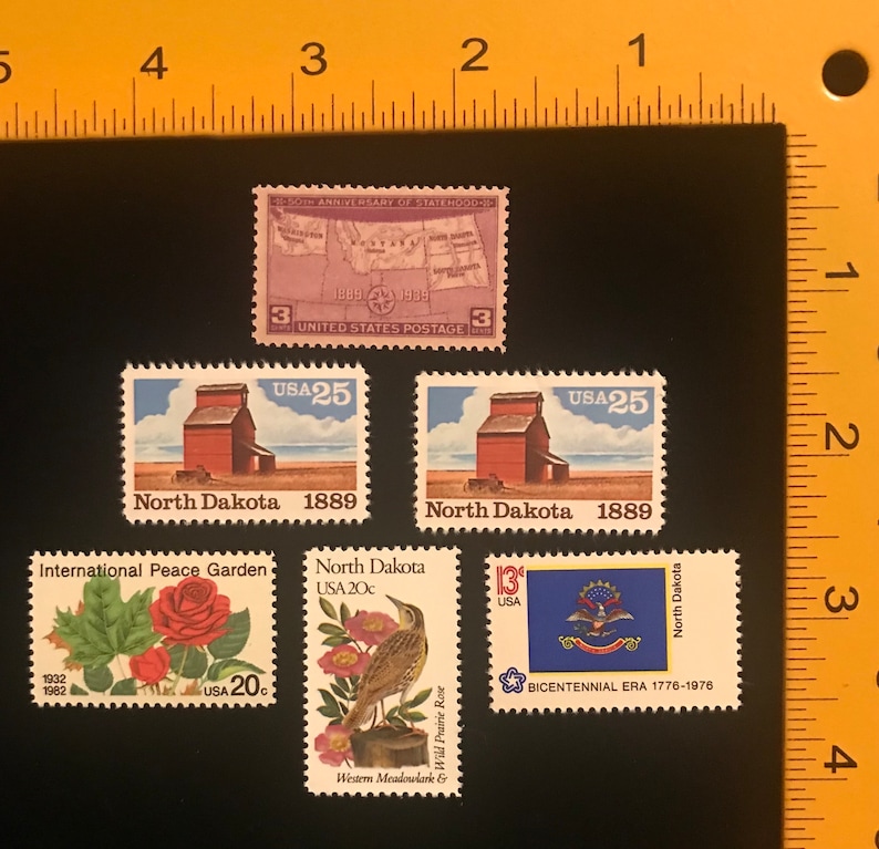 Pu&ograve; includere: Cinque francobolli vintage con immagini del Dakota del Nord. I francobolli raffigurano una mappa del Dakota del Nord, un silo per cereali, una rosa, un'allodola dei prati e il sigillo dello stato. I francobolli sono degli anni '70 e '80.