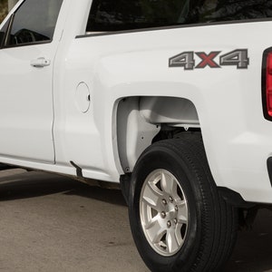 May include: White pickup truck with a 4x4 decal on the side of the bed. The truck has a black bumper and a black tailgate.