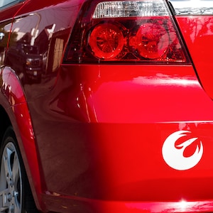 May include: A red car with a white Rebel Alliance symbol sticker on the back bumper.