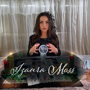 Puede incluir: Una mujer sentada en una mesa con una bola de cristal, cartas de tarot y velas. El texto "Izaura Moss" está escrito en la mesa frente a ella.