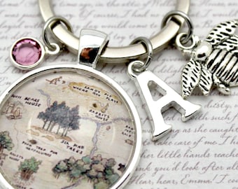 May include: Silver keychain with a round pendant featuring a map illustration, a pink gem, a letter "A" charm, and a bee charm. The keychain is attached to a silver ring.
