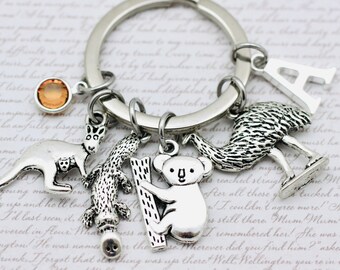 May include: A silver keychain with a variety of charms, including a kangaroo, koala, emu, and a letter 'A'. The charms are attached to a silver ring.