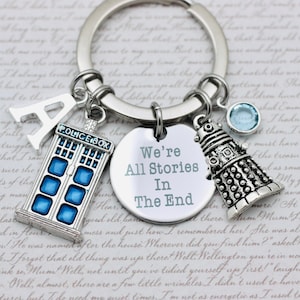 May include: A silver keychain with a blue TARDIS charm, a silver Dalek charm, a blue crystal charm, and a silver charm with the text "We're All Stories In The End".