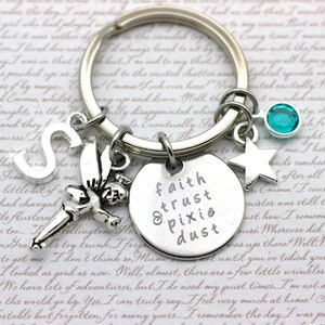 May include: Silver keyring with a charm that says "faith trust & pixie dust" and other charms including a fairy, a star, and a blue crystal.