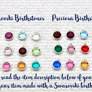 May include: A display of colorful birthstone charms, with the text "Swarovski Birthstones" and "Preciosa Birthstones" at the top. The charms are arranged in two rows, with each row containing 12 charms.