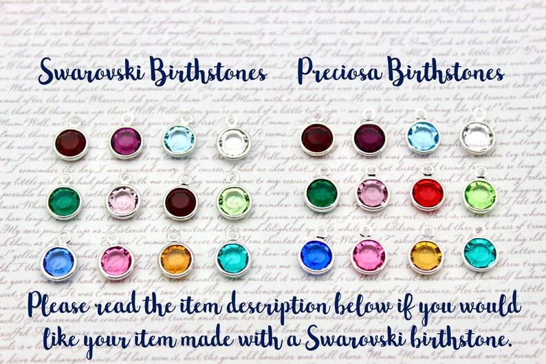 May include: A display of colorful birthstone charms, with the text "Swarovski Birthstones" and "Preciosa Birthstones" at the top. The charms are arranged in two rows, with each row containing 12 charms.