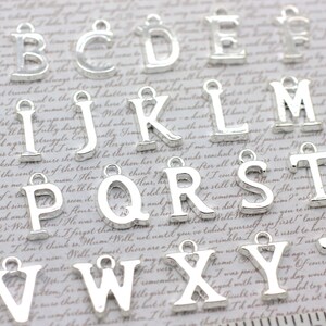 May include: Silver alphabet letter charms with a loop for hanging. The letters are arranged in alphabetical order from A to Z.