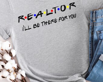 May include: A light gray t-shirt with the word "REALTOR" in black, with the letters in the style of the TV show "Friends", and the phrase "I'll be there for you" in black. The shirt is paired with blue jeans.