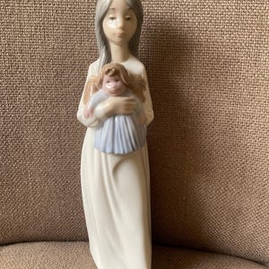 Vintage NAO by Lladro Figure of a girl with grey hair holding her doll (9.5 ins h) Unboxed 1990