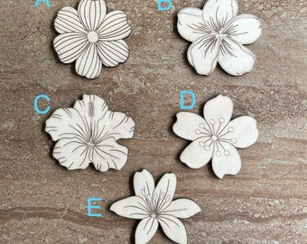 May include: Five wooden flower cutouts with various floral designs. The flowers are unpainted and feature detailed line drawings of petals and centres. The cutouts are arranged on a brown surface.