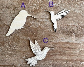 May include: Three wooden hummingbird cutouts in various poses. One is a solid silhouette, another has outstretched wings, and the third has detailed wing and tail feathers. The cutouts are unpainted and made of light-colored wood.
