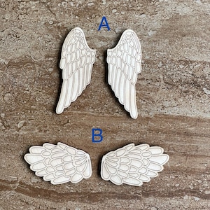 May include: Two sets of wooden angel wings. The first set is larger and has a more detailed design. The second set is smaller and has a simpler design.