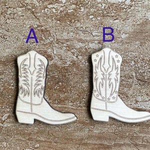 May include: Two wooden cutout cowboy boot ornaments, one with a simple design and the other with a star pattern. The boots are painted white and are labeled A and B.