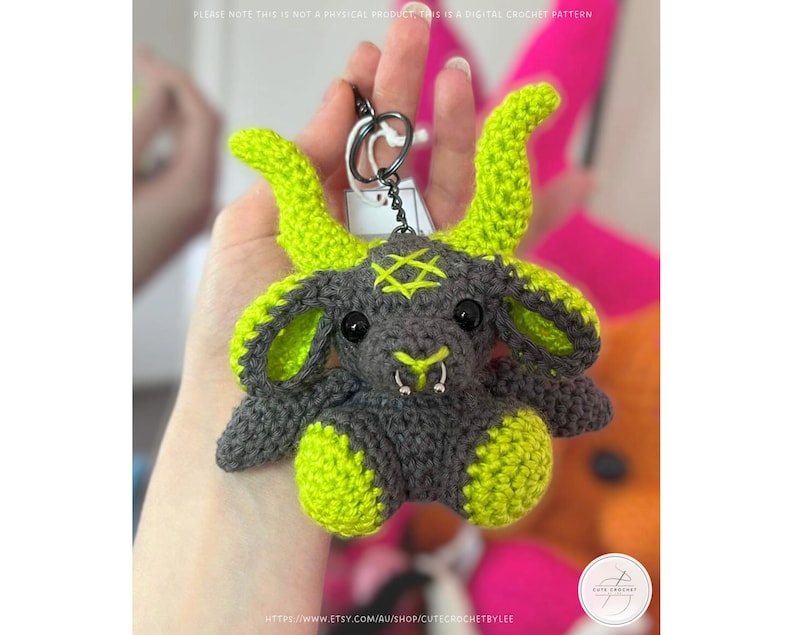 May include: A crocheted keychain featuring a gray and neon green goat-like creature with a pentagram on its head. The keychain has a silver ring and a tag. The text on the image says "PLEASE NOTE THIS IS NOT A PHYSICAL PRODUCT THE DIGITAL CROCHET PATTERN".