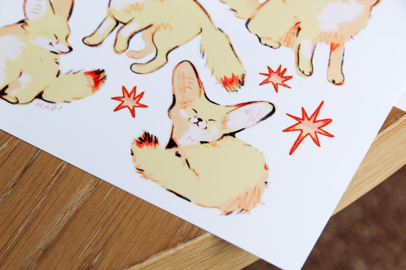 May include: A set of four illustrated fennec foxes with orange and yellow fur. The foxes are in various poses, including sitting, standing, and looking up. The background is white with red starbursts.