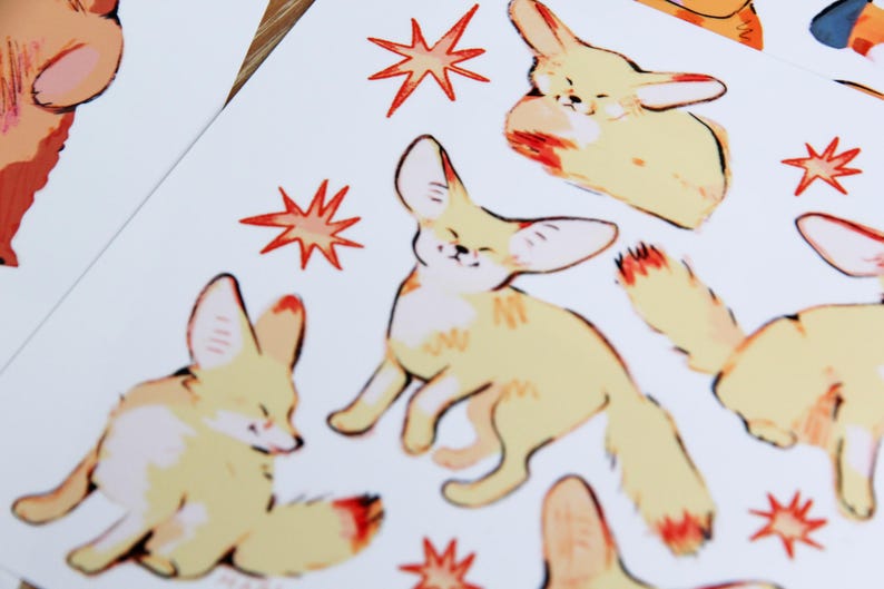 May include: A sheet of stickers featuring illustrations of fennec foxes in various poses. The foxes are depicted in a light yellow color with orange accents. The background is white with red starburst designs.