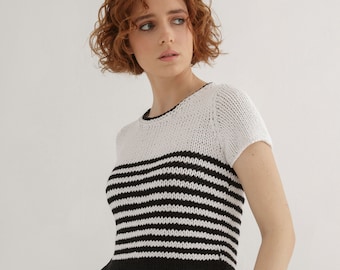 May include: A white and black striped knit top with short sleeves. The top has a round neckline and is cropped.