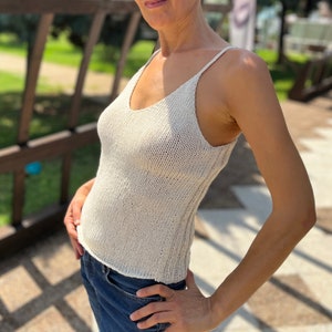 May include: A white crochet tank top with a v-neckline and thin straps.