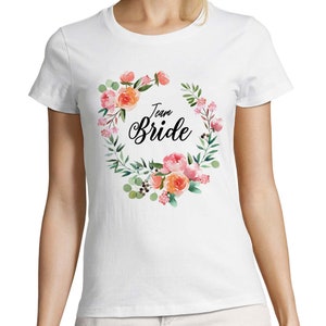 May include: White t-shirt with a floral wreath design and the text "Team Bride" in black.