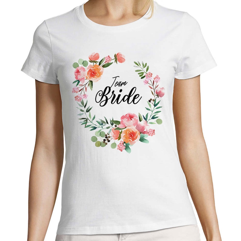 May include: White t-shirt with a floral wreath design and the text "Team Bride" in black.