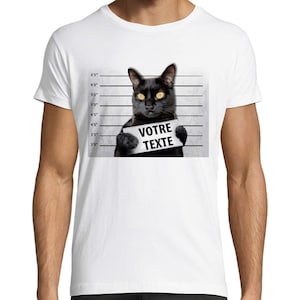 Könnte beinhalten: Ein weißes T-Shirt mit einer schwarzen Katze, die ein Schild mit der Aufschrift "VOTRE TEXTE" hält. Die Katze ist im Stil eines Fahndungsfotos mit einer Höhenangabe und Linien dahinter.