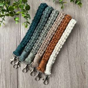 May include: Set of six macrame keychains in shades of green and beige with silver key rings.