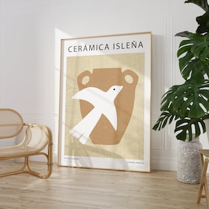 以下が含まれることがあります： 黒い文字で「CERÁMICA ISLEÑA」と書かれたミニマルなポスター。ポスターには、茶色の陶器の壺から飛び出す白い鳥が描かれている。「las islas canarias」と「estudio rebecca」の文字がポスターの下部に書かれている。