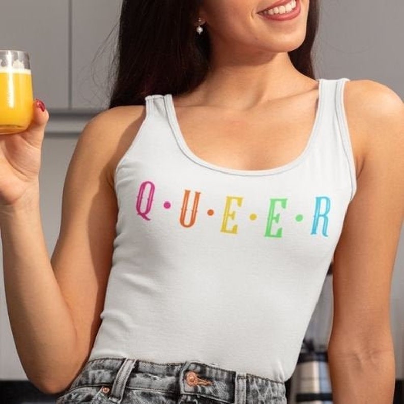 May include: White tank top with the word "Q.U.E.E.R." printed in rainbow colors.