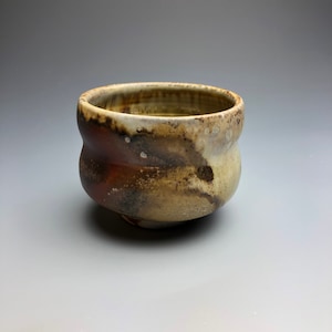 May include: A small, brown and white ceramic bowl with a slightly wavy rim. The bowl has a rustic, handmade look.