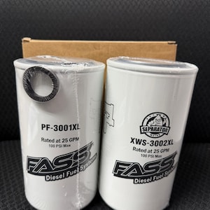 May include: Two white cylindrical FASS Diesel Fuel Systems filters, models PF-3001XL and XWS-3002XL, with black text and logos. The filters are rated at 25 GPM and 100 PSI Max. They are packaged in clear plastic.