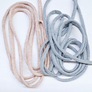 May include: Two spools of sparkly cord, one in a light pink color and the other in a light gray color.