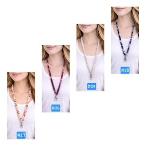 Op de afbeelding: Vier stoffen lanyards met metalen karabijnsluitingen. Nummer 17 is beige met rode en groene bloemmotieven. Nummer 26 is een paars en magenta kleurverloop. Nummer 24 is een cr&egrave;mekleurig en wit geweven textuur. Nummer 28 is marineblauw met witte bloemen.