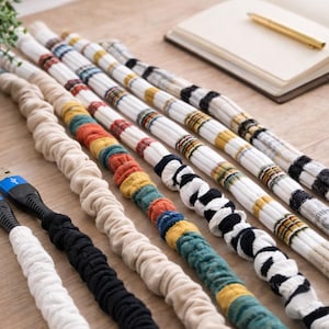 May include: A white ceramic mug with a black handle and the text "But First, Coffee" in a bold, black font. The mug is set against a blurred background, suggesting a cozy setting.