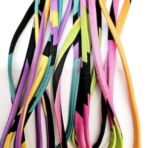 May include: A close-up of colorful fabric trim with a geometric pattern in shades of pink, yellow, green, teal, purple, and black.