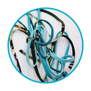 May include: A close-up of a pile of colorful elastic cord, featuring a mix of teal, green, and black colors. The cord is made of a soft, stretchy material and is perfect for crafting projects.