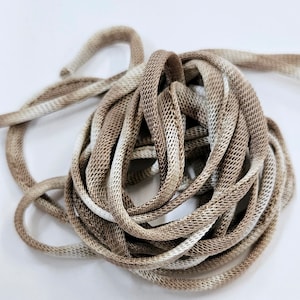 May include: A close-up of a brown and white shoelace with a textured, woven design.