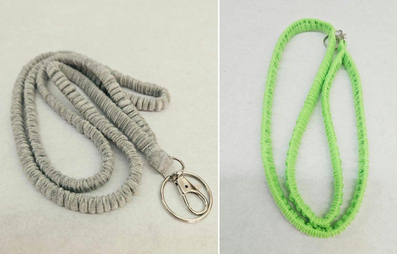 May include: A grey fabric lanyard with a silver-toned metal lobster clasp and a split ring, alongside a bright lime green fabric lanyard. Both lanyards feature a textured, ribbed surface design and are constructed from a soft, flexible material.