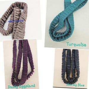 May include: Four fabric headbands in warm mocha, turquoise, dusty eggplant, and stormy blue. Each headband features a gathered, elasticized design with a soft, matte texture. The colors are labeled as warm mocha, turquoise, dusty eggplant, and stormy blue.