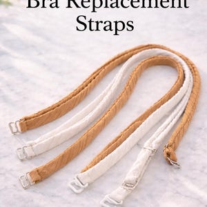 May include: Bra replacement straps in tan and white. The straps are made of a textured fabric and have metal clasps. The text "Bra Replacement Straps" is at the top of the image.