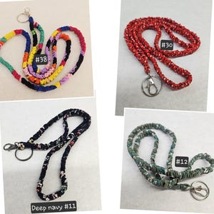 K&ouml;nnte beinhalten: Vier Stoff-Lanyards mit Metall-Schl&uuml;sselringen und Karabinerverschl&uuml;ssen. Lanyard #38 zeigt ein mehrfarbiges Patchwork-Muster. Lanyard #30 ist rot mit wei&szlig;en Punkten. Lanyard #11 ist tief dunkelblau mit Blumenmuster. Lanyard #12 ist gr&uuml;n mit Blumenmuster.