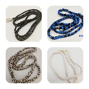 K&ouml;nnte beinhalten: Vier Stoff-Lanyards mit Metallverschl&uuml;ssen. Eines ist schwarz mit wei&szlig;en Punkten, eines ist blau-schwarz gemustert mit dem Text #26, eines ist beige mit braunem Leopardenmuster und eines ist einfarbig cremewei&szlig;. Jedes Lanyard hat ein gerafftes Stoffdesign.