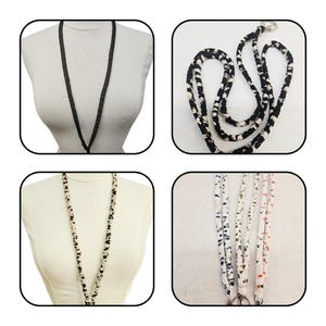 K&ouml;nnte beinhalten: Eine Kollektion von Stoff-Lanyards mit verschiedenen Mustern und Farben. Das Set enth&auml;lt ein einfarbiges schwarzes Lanyard, ein schwarz-wei&szlig; gemustertes Lanyard, ein beige-schwarz gepunktetes Lanyard und drei wei&szlig;e Lanyards mit kleinen Blumenmustern.