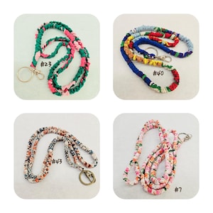 K&ouml;nnte beinhalten: Vier Stoff-Lanyards mit Metall-Schl&uuml;sselringen und Karabinerverschl&uuml;ssen. Nummer 23 ist gr&uuml;n und pink, Nummer 40 ist mehrfarbig, Nummer 43 zeigt ein kleines Blumenmuster und Nummer 7 weist einen pink-wei&szlig;en Blumendruck auf dem Stoff auf.