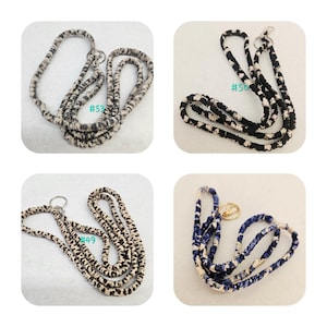 K&ouml;nnte beinhalten: Vier Stoff-Lanyards mit Metallringen. Oben links ein grau-wei&szlig;es Muster, oben rechts ein schwarz-wei&szlig;es Muster mit #50, unten links ein beigefarbenes Leopardenmuster mit #49 und unten rechts ein blau-wei&szlig;es Muster.